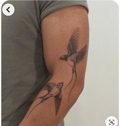 a man with a tattoo on his arm has two birds flying in the same direction