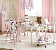 a child's room with pink furniture and accessories on the table in front of a window