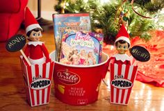 an elf is sitting in a bucket next to some movies