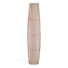 a tall wooden vase sitting on top of a white floor next to a wire lamp