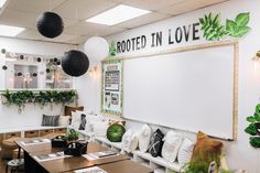 a room with tables, couches and plants on the wall in front of it