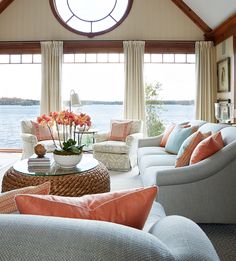 a living room filled with furniture and a large window overlooking the water in front of it