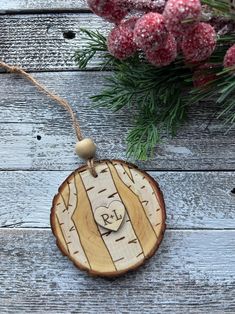 a wooden ornament hanging from a string on top of a table next to flowers