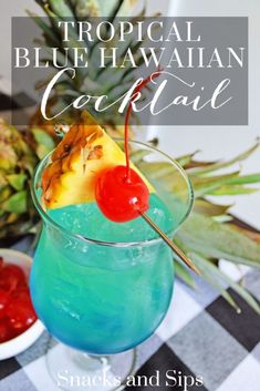 a blue hawaiian cocktail in a glass with a cherry on the rim and pineapple