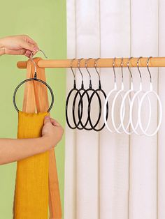 a person is holding several pairs of hoop earrings in front of a rack with five rings hanging from it