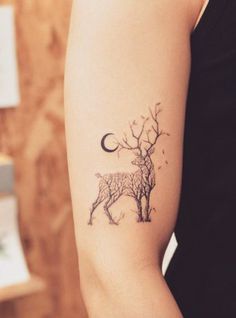 a woman's arm with a deer tattoo on it, and the moon in the background