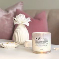 a white vase sitting on top of a table next to a candle and a bowl