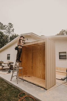 a man is standing on a ladder in front of a house that's being built