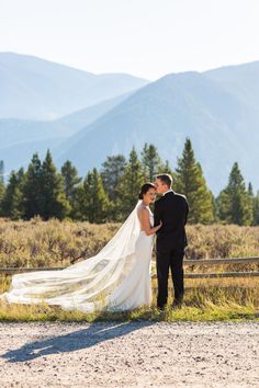 a bride and groom standing in front of mountains