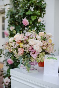 a bouquet of flowers sitting on top of a white dresser next to a card holder