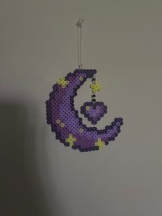 a crocheted purple and yellow moon hanging from a hook on a white wall