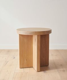 a wooden table sitting on top of a hard wood floor next to a white wall