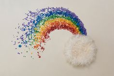 a rainbow made out of confetti and sprinkles on a white surface