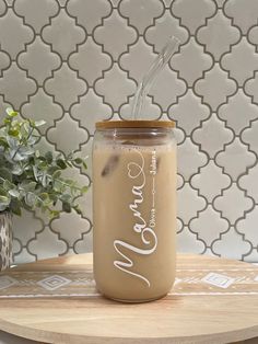 a glass jar with a straw in it sitting on a table next to a potted plant