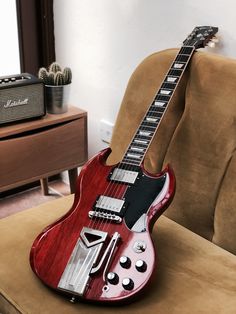 a red electric guitar sitting on top of a couch