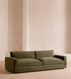 a green couch sitting on top of a hard wood floor next to a white wall