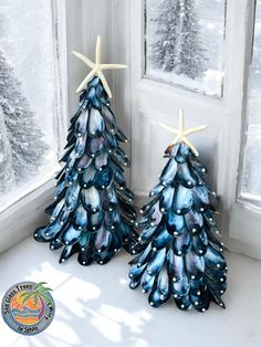 two blue christmas trees sitting in front of a window