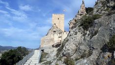 an old castle on the side of a mountain with stairs going up it's side