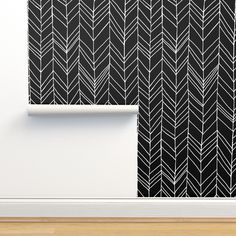 a black and white wallpaper with an arrow pattern on it, next to a wooden floor