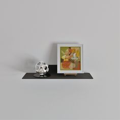 a soccer ball sitting on top of a black shelf next to a framed photo and an ornament