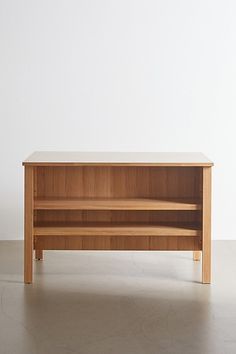 a wooden shelf sitting on top of a floor next to a white wall in an empty room