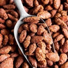 a spoon full of sugared almonds sitting on top of a pile of other nuts