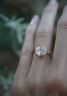 a woman's hand with an engagement ring on her finger, showing the center stone