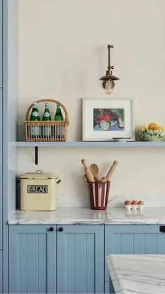 a kitchen with blue cabinets and white marble counter tops is pictured in this image, there are various items on the shelves