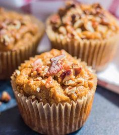 three muffins sitting on top of a table next to each other with nuts