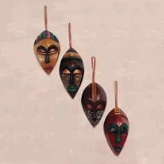 three wooden masks hanging from strings on a wall