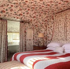 a bed with red and white bedspread sitting under a pink flowered ceiling