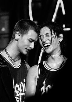 two young men standing next to each other with their faces covered by hair and piercings