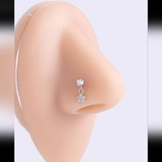 a close up view of an ear with two small diamonds on the middle one side