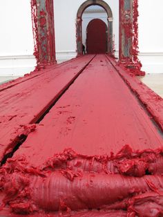 a large red piece of art sitting in the middle of a floor covered in paint