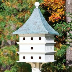 a white bird house in front of some trees