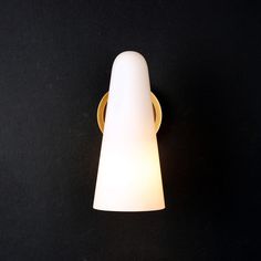 a light that is on the side of a black wall with a white lamp shade