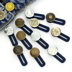 several different types of buttons are placed in front of a pair of jeans pockets