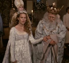 two people dressed in medieval clothing standing next to each other and one person wearing a crown