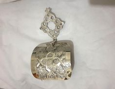 a silver locke with an intricate design on it's chain is laying on a white sheet