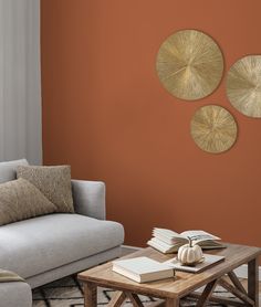 a living room with orange walls and three circular metal wall art pieces on the wall