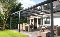 a patio covered in furniture and plants next to a house