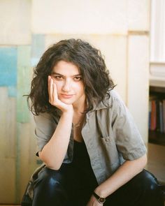 a woman sitting on the floor with her hand under her chin