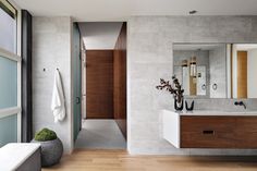 a bathroom with a sink, mirror and bathtub next to a wall mounted toilet