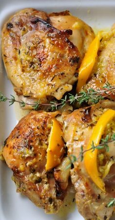 chicken thighs with oranges and herbs on a white plate, ready to be eaten