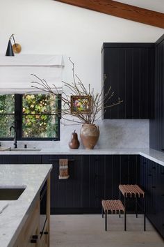 a kitchen with black cabinets and marble counter tops, an island bench and stools