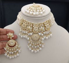 a white mannequin with gold jewelry on it's neck and hands holding the necklace