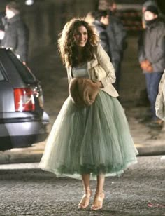 a woman in a green dress is walking down the street