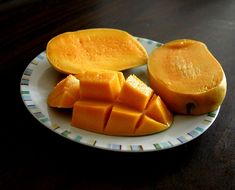 a white plate topped with sliced mangoes on top of a wooden table