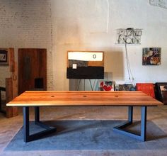 a wooden table sitting in the middle of a room with white walls and black metal legs