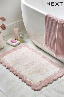 a bathroom with a pink rug and white bathtub